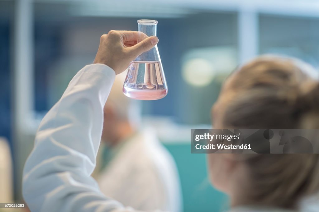 Woman in lab examining liquid in Erlenmeyer flask