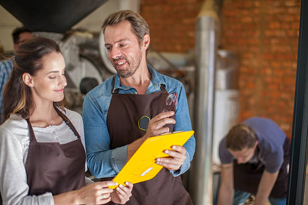 people roasting coffee looking at clipboard - professional coffee roaster stock pictures, royalty-free photos & images