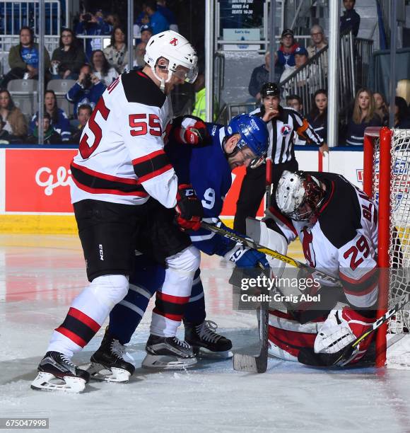 Mike Sislo of the Toronto Marlies digs for loose puck against goalie Mackenzie Blackwood and Viktor Loov of the Albany Devils during game 3 action in...