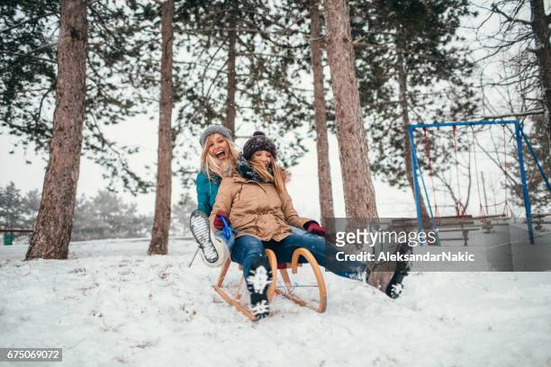 due fidanzate slittino in una giornata invernale - capelli castani foto e immagini stock