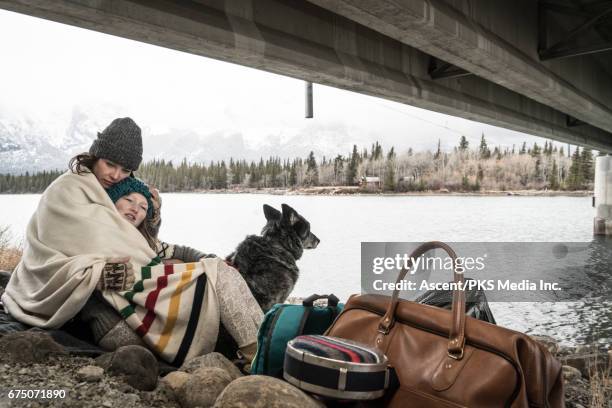 mother and daughter huddle at roadside, with belongings - homelessness stock pictures, royalty-free photos & images