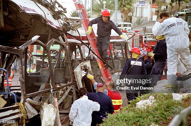 Israeli police and firemen investigate the blown-apart remains of a passenger bus December 2, 2001 in the northern city of Haifa. Fifteen people were...