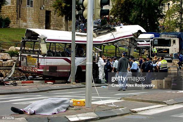 Victim's body lies across the street from the blown-apart remains of a passenger bus December 2, 2001 in the northern city of Haifa. Fifteen people...