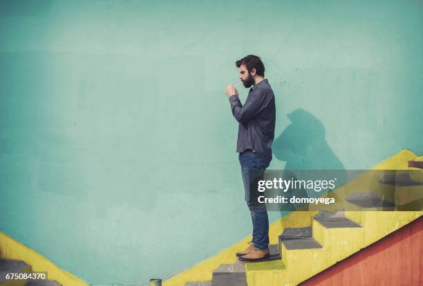 bearded hipster going down the stairs and lighting cigarette - quitting smoking stock pictures, royalty-free photos & images