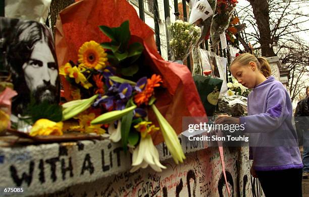 Girl touches the wall of Abbey Road Recording Studios December 2, 2001 after the death of musician George Harrison. An impromptu shrine to the...