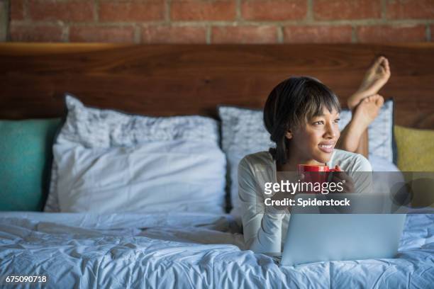 young african american female in bed with laptop - toothy smile stock pictures, royalty-free photos & images
