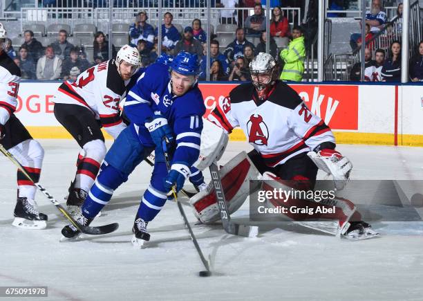 Andreas Johansson of the Toronto Marlies controls the puck in front of goalie Mackenzie Blackwood and Vojtech Mozik of the Albany Devils during game...