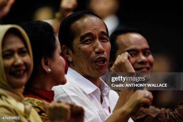 Indonesian President Joko Widodo sings as he watches the rock band Slank with his wife Iriana and Indonesian Consul General to Hong Kong Tri Tharyat...