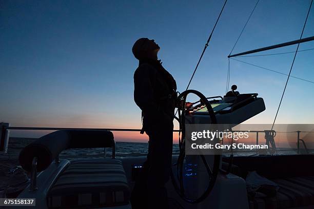 mature male checks the wind on 63 ft sailboat - sailboat silhouette stock pictures, royalty-free photos & images