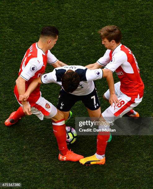 Granit Xhaka of Arsenal and Nacho Monreal of Arsenal attempt to tackle Heung-Min Son of Tottenham Hotspur during the Premier League match between...