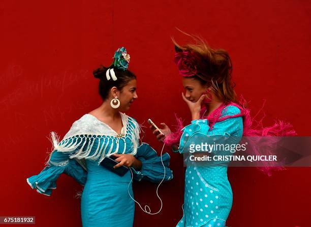 Two girls wearing traditional Sevillian dresses talk during the "Feria de Abril" in Sevilla on April 30, 2017. - The fair dates back to 1847 when it...
