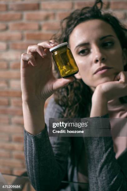 woman holding and looking on a pill. - addiction recovery stock pictures, royalty-free photos & images