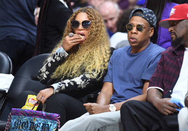 Beyoncé come papas fritas mientras Jay Z observa el juego en el Juego 7 de la primera ronda de los playoffs de la Conferencia Oeste de la NBA en el Staples...