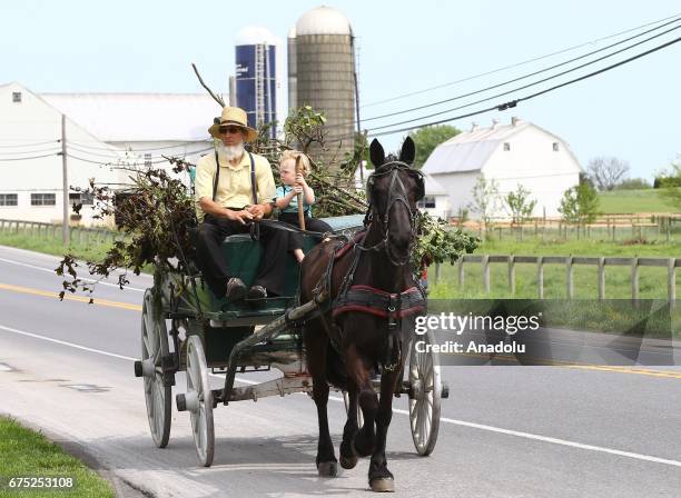 Amish man ride an amish horse with a boy in Central Pennsylvania, United States on April 30, 2017. Central Pennsylvania is home to an iconic set of...