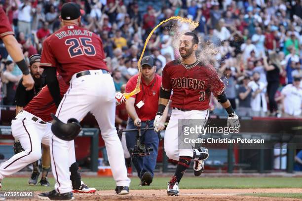 Daniel Descalso of the Arizona Diamondbacks is congratulated at home plate by teammates after hiting a two run home run to defeat the Colorado...