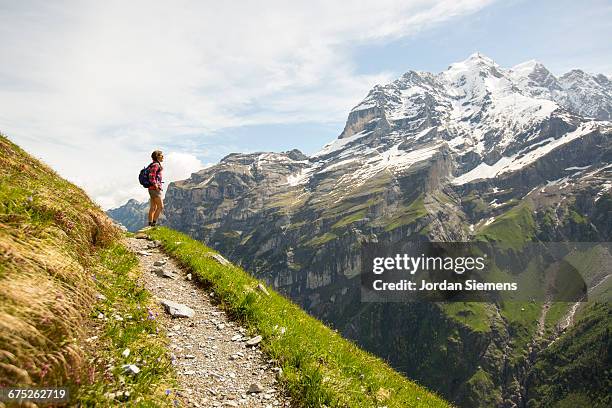 a woman hiking a trail in the alps - schweiz wandern stock-fotos und bilder