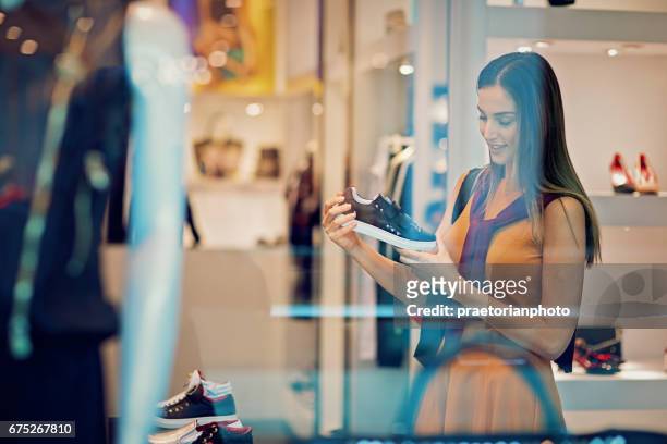 junges schönes mädchen sucht schuhe in der mall - fashion boutique stock-fotos und bilder