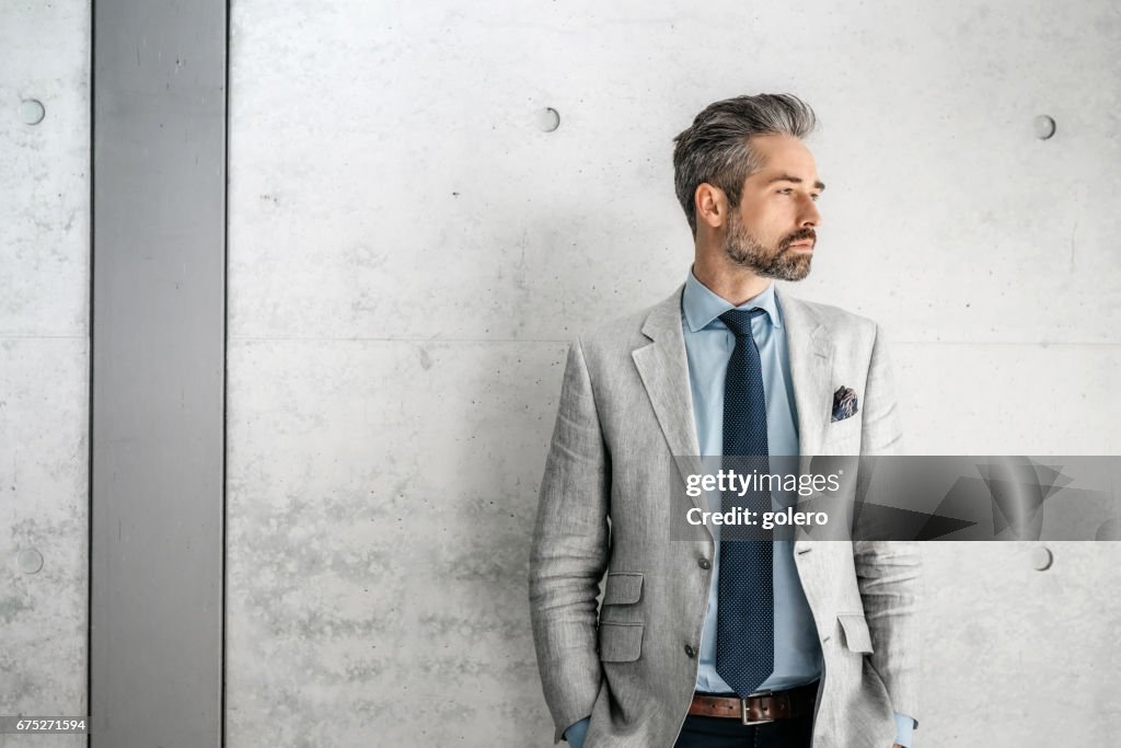 Elegant handsome bearded businessman standing with dog  in business district