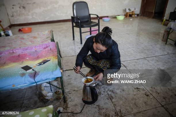 This picture taken on March 30, 2017 shows a Jin opera performer cooking in her temporary accommodation at an outdoor theatre in Yu county, or...