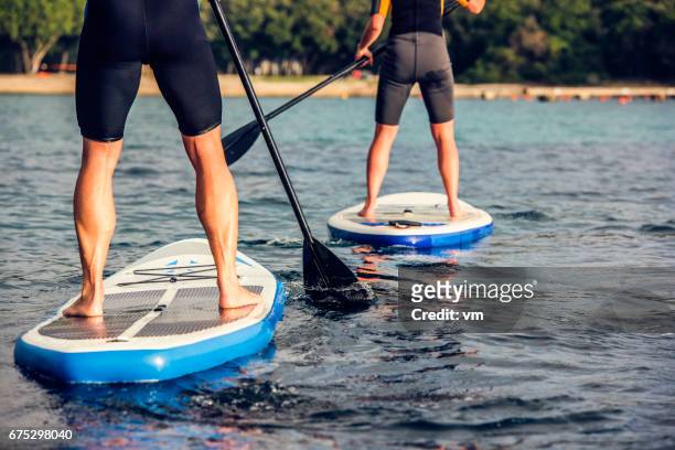 rear view of two paddle boarder's legs - croatia people stock pictures, royalty-free photos & images