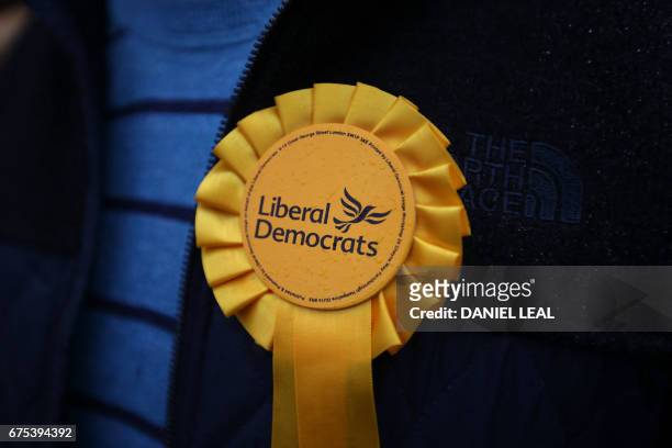 Supporter wears a party rosette as he listens to Britain's Liberal Democrats leader, Tim Farron speak at the start of his battle bus tour, in...