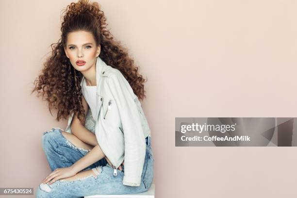 hermosa chica sentada en la habitación tipo estudio - rizado peinado fotografías e imágenes de stock