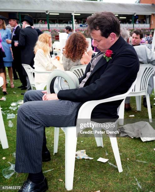 Man holding a top hat takes a nap in a white plastic chair at Royal Ascot. June 2000.