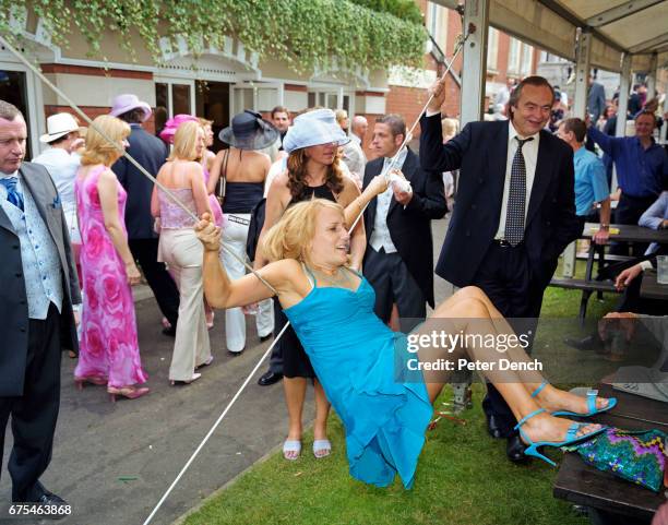 Female visitor to Royal Ascot hangs from the support of a hospitality tent. June 2002.