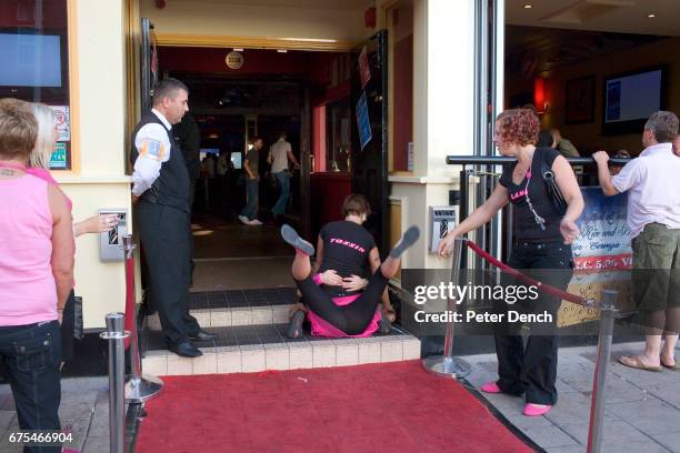 Door security man watches two women out in Blackpool with a hen party fool about on the floor of Nellie Deans Piano Bar on the North Promenade. A...