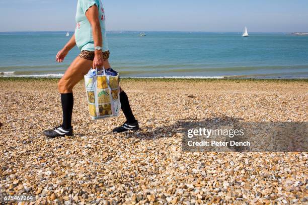 Man takes an early morning stroll along Portsmouth's pebble beach. Portsmouth is a city located in the county of Hampshire on the southern coast of...