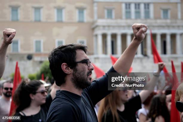 Protesters raise their fists and sing the anthem of the Socialist International, outside the Parliament, in central Athens during the May Day...