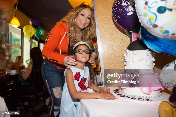 Monroe Cannon poses next to her birthday cake as mom Mariah Carey looks on at Disneyland on April 30, 2017 in Anaheim, California.