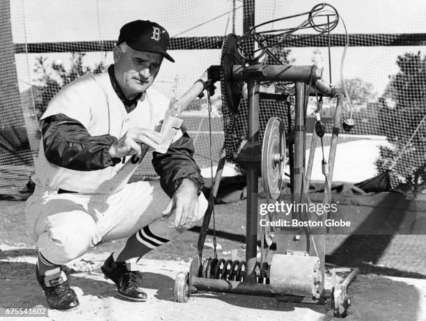 Boston Red Sox first base coach Bobby Doerr examines a batting practice machine during Red Sox Spring Training in Winter Haven, FL on Feb. 27, 1967.