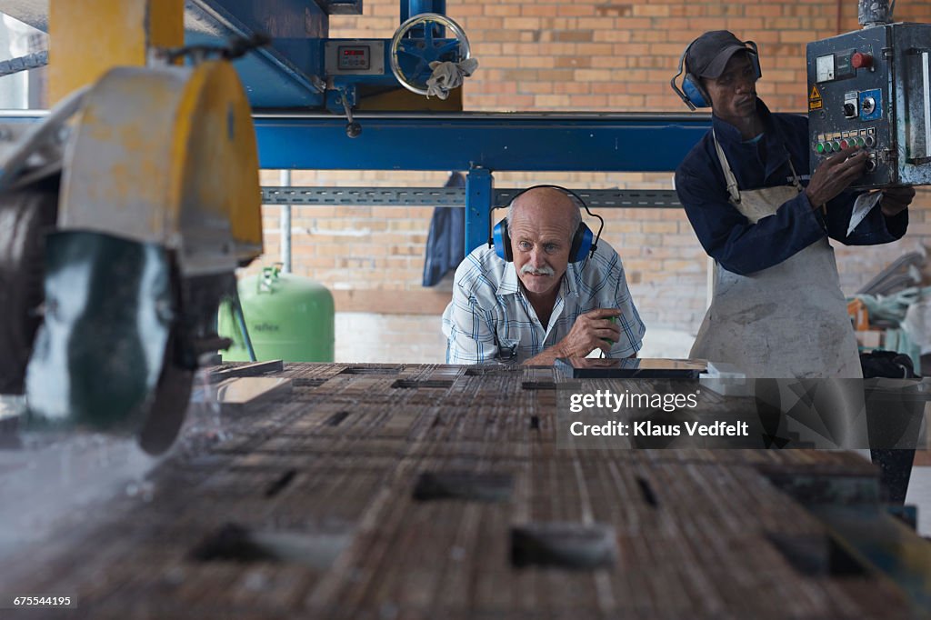 Co-workers working with stone cutting machine
