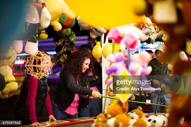 teenage girl playing at fairground stall - toy fair stockfoto's en -beelden