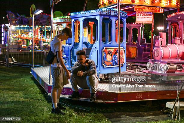 teenager showing phone to a friend at a fairground - unfilteredtrend stock pictures, royalty-free photos & images