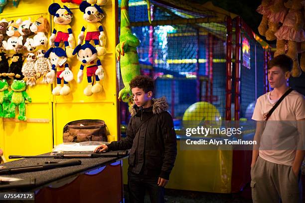 teenage boys at a fairground stall at night - unfilteredtrend stock pictures, royalty-free photos & images