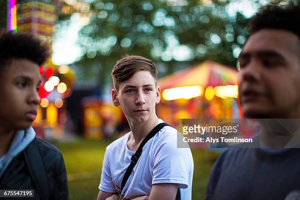 portrait of teenage boy with friends at fairground - serious teenager boy stock-fotos und bilder
