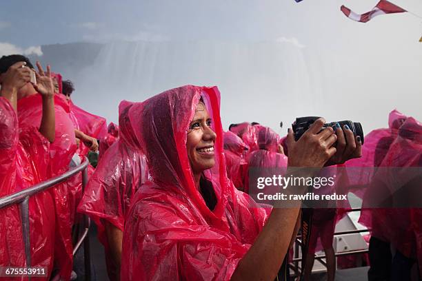 a young woman photographing on a tourist boat - niagarawatervallen stockfoto's en -beelden