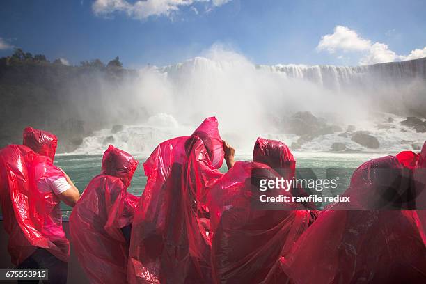 tourists on a boat viewing niagra falls - niagara falls stock pictures, royalty-free photos & images