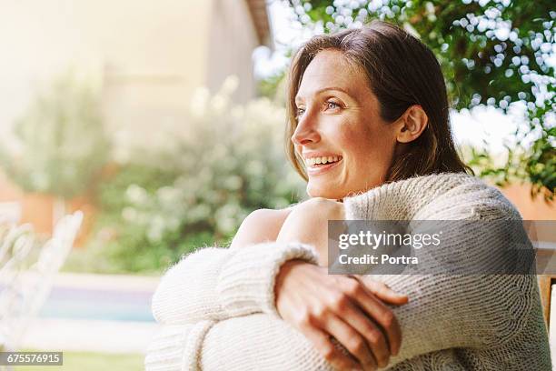 close-up of smiling woman sitting outdoors - hugging knees stock pictures, royalty-free photos & images