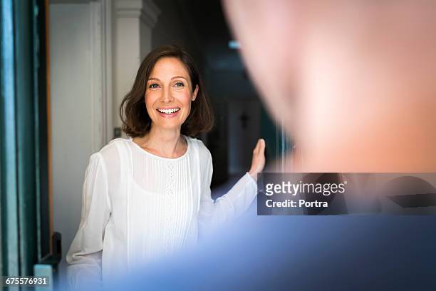 smiling mid adult woman standing on entrance - open door stock pictures, royalty-free photos & images