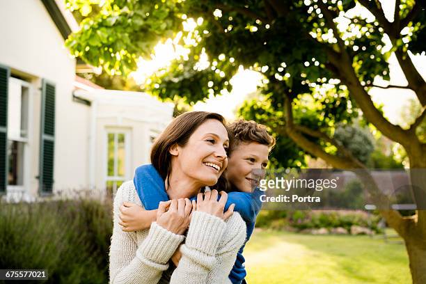 boy embracing mother outside house in yard - mother and son stock pictures, royalty-free photos & images