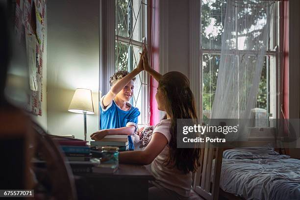 brother giving hi-fi to teenager at study table - brother sister stock pictures, royalty-free photos & images