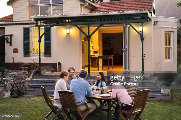 family having food while sitting outside house - family gathering stockfoto's en -beelden