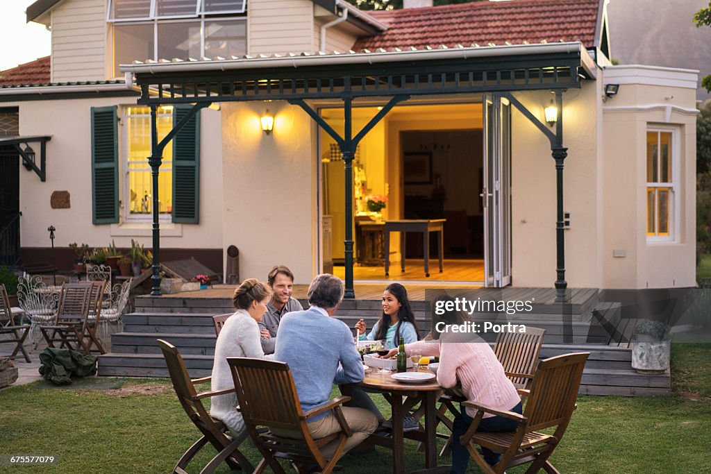 Family having food while sitting outside house