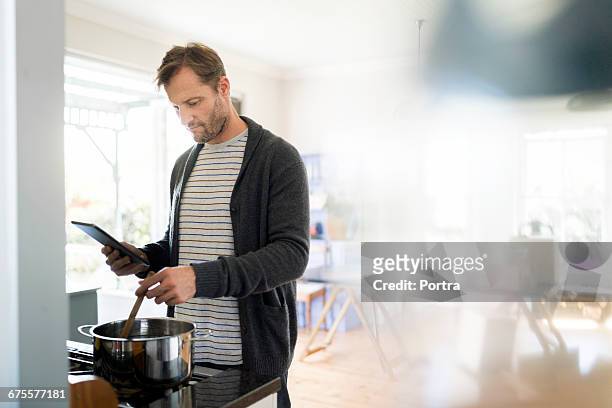 man using digital tablet while cooking in kitchen - digital techniques ストックフォトと画像