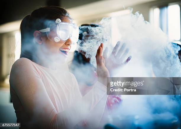 smiling girl gesturing while surrounded by smoke - wissenschaftliches experiment stock-fotos und bilder