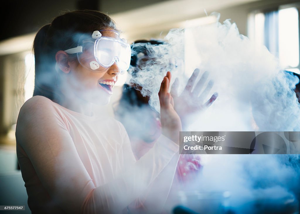 Smiling girl gesturing while surrounded by smoke