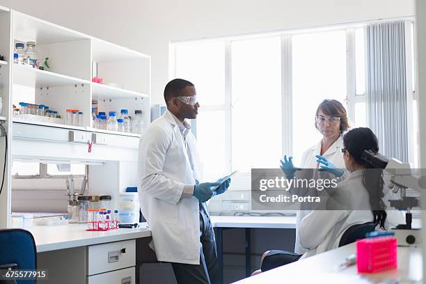 scientists discussing in meeting at laboratory - onderzoeksfaciliteit stockfoto's en -beelden